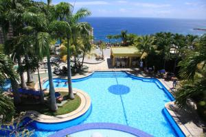 Macuto奥莱加勒比酒店的享有棕榈树游泳池和大海的顶部景致