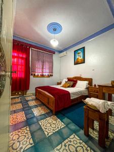 舍夫沙万Hôtel Al Kalaa的一间卧室设有一张床和一个红色的窗户