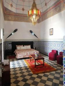 Sidi Abd el KaderRiad Freija-TAROUDANT的一间卧室配有一张床、一张桌子和一个吊灯。