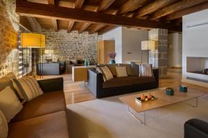 UrizHotel Rural Torre de Úriz的客厅配有棕色家具和石墙