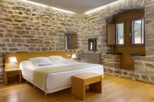 UrizHotel Rural Torre de Úriz的卧室配有一张石墙内的大床