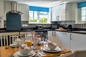 CarnbreaFinest Retreats - Trethew Cottage的厨房配有带盘子和玻璃杯的木桌