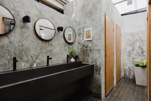 曼谷Napshot Guesthouse的浴室设有黑色水槽和两面镜子