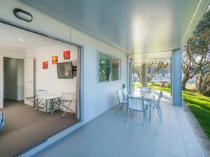 怀蒂昂格Marinaview - Whitianga Holiday Apartment的一个带桌椅的庭院和一个窗户。