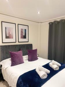 伦敦Stylish En Suite double room Kensington的一间卧室配有一张带紫色和白色毛巾的床