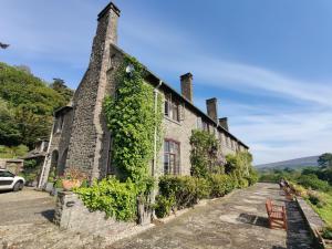 波洛克Luxury Bed And Breakfast at Bossington Hall in Exmoor, Somerset的一座有常春藤的古老石头建筑