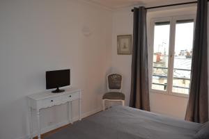 巴黎红磨坊二号公寓的一间卧室配有一张床、一台电视和一个窗口