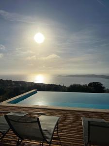卡尔热斯Villa Cargese的一个带两把椅子的游泳池,阳光在天空中