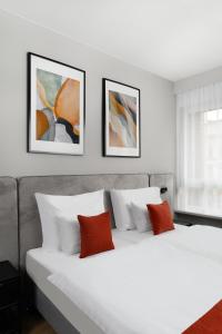 布达佩斯Florin Apart Hotel的卧室配有一张白色床,墙上挂有三幅画作