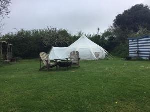 金斯布里奇Horsemans Stargazing Tent的草顶帐篷,配有两把椅子和一张桌子