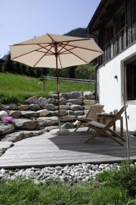 GsteigAlpen Charme - Chalet d'Hôtes et SPA的一个带椅子和遮阳伞的庭院