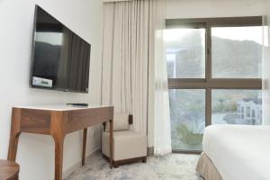 SharmThree Bedroom Apartment at Address Residence Fujairah的酒店客房配有一张床、一张书桌和一台电视。