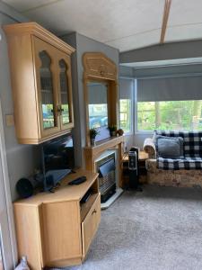 麦克尔斯菲尔德Monks Heath fold mobile home的客厅配有书桌、电视和沙发