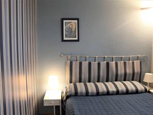 卢贝新城Appartement Villeneuve-Loubet, 2 pièces, 3 personnes - FR-1-252A-102的一间卧室配有一张带条纹毯子和两盏灯的床。