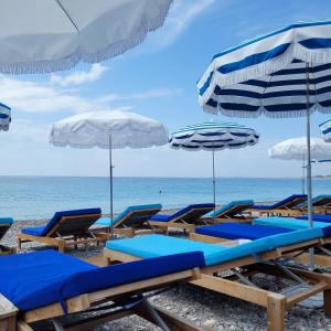 尼斯Haliviera - Golden Square, 1min from beach的海滩上的一组沙滩椅和遮阳伞