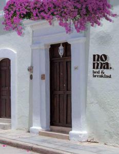 圣克里斯托瓦尔-德拉斯卡萨斯Noma Bed & Breakfast的白色的建筑,带棕色的鲜花门