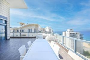 内坦亚Luxury Penthouse in Netanya的阳台配有白色桌子和白色椅子