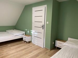 NiesiołowiceDomek Oliwkowy Balia z Jacuzzi KASZUBY的一间卧室设有两张床,拥有绿色的墙壁