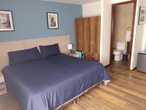 波哥大Hotel Boutique Quinta Camacho的一间带蓝色床的卧室和一间浴室