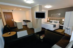 贝洛奥里藏特Allia Gran Pampulha Suites的酒店客房,配有床和电视
