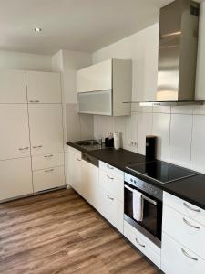 布雷根茨Penthouse im Zentrum von Bregenz的厨房配有白色橱柜和黑色台面