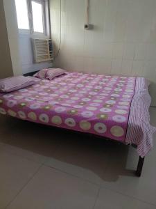 巴特那OYO Swaraj Guest House的一张带紫色和白色棉被的大床