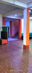 巴特那SPOT ON The Green Resort Restaurant的一间空房间,铺有木地板,拥有橙色和白色的柱子