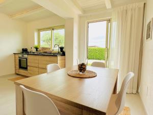 锡拉库扎Plemmirio Apartment的厨房配有木桌和白色椅子
