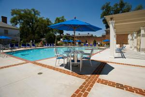 威廉斯堡威廉斯堡旅馆傲途格精选酒店 的一个带桌子和蓝伞的游泳池