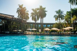 伊瓜苏维瓦卡塔瑞斯度假酒店的一座棕榈树和遮阳伞的大型游泳池