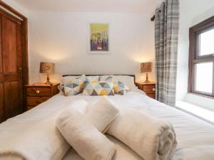 格兰奇奥沃桑茨Daffodil Cottage的一间卧室配有带白色床单和枕头的床。