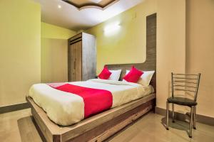 贾姆谢德布尔OYO Flagship Dream Connect的一间卧室配有一张带红色枕头的床和一把椅子