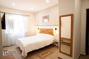 Hotel Rural el Turuñuelo的卧室配有白色的床和镜子