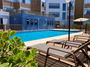 拉古纳Residence Farol - Loft 204的一座带椅子和遮阳伞的游泳池