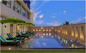 帕纳吉Fortune Miramar, Goa - Member ITC's Hotel Group的一个带躺椅的游泳池和一间酒店