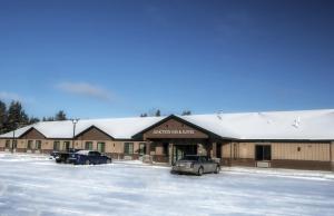 BabbittJunction Inn Suites & Conference Center的一座有汽车停放在雪地覆盖停车场的建筑