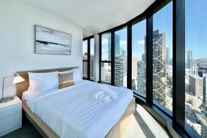 墨尔本Highrise best location 2baths的一间卧室配有一张带白色床单和大窗户的床。