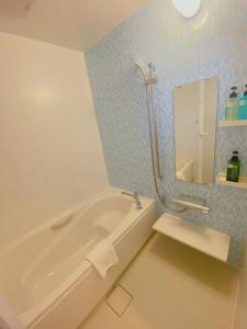 那霸KOHALA　HOTEL的浴室配有白色浴缸和镜子