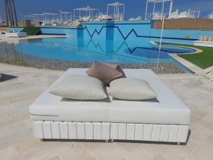 朱拜勒Four Seasons Halat的泳池前的白色沙发,配有两个枕头