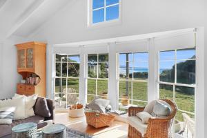 FalmouthWhite Shell Cottage - Woodfire & Beachfront的带沙发、椅子和窗户的客厅
