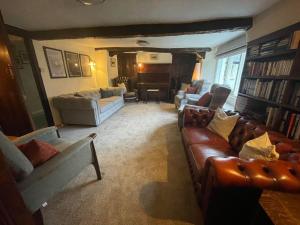 博罗代尔谷Seatoller House的客厅配有真皮沙发和钢琴