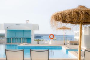 桑帕克Beach Club Menorca的一个带椅子和草伞的游泳池