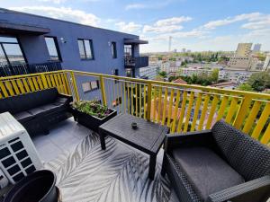 蒂米什瓦拉AZUR Apartment的阳台配有沙发、桌子和黄色围栏。