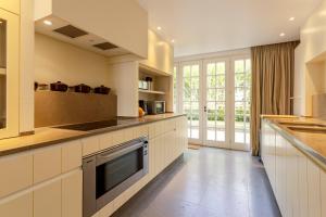 德帕内Villa Pauline的大型厨房配有白色橱柜和大窗户
