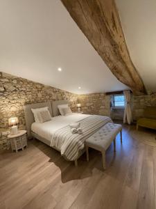 圣艾米隆La Maison du Clocher的一间卧室设有一张大床和石墙