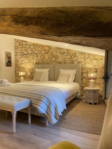 圣艾米隆La Maison du Clocher的一间卧室设有一张大床和石墙