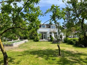 多德雷赫特Tiny house in tuin van de statige villa Mariahof的享有带庭院的白色房屋的外部景色