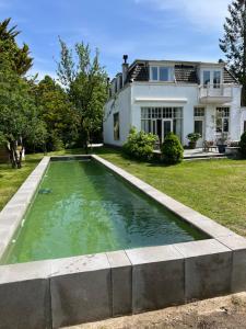 多德雷赫特Tiny house in tuin van de statige villa Mariahof的房屋前的游泳池