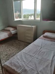 蒂瓦特Dena apartman Tivat的一间卧室设有两张床、一个梳妆台和两个窗户。