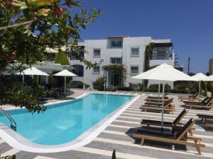 古瓦伊Sandy's Cycladic Style Apartment的一座带椅子和遮阳伞的游泳池位于一座建筑旁边